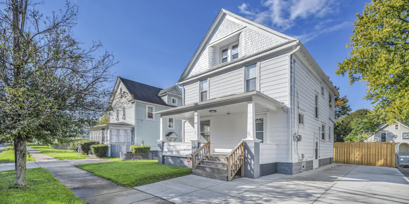 White two-story house with lap siding, a covered front porch and a long concrete driveway