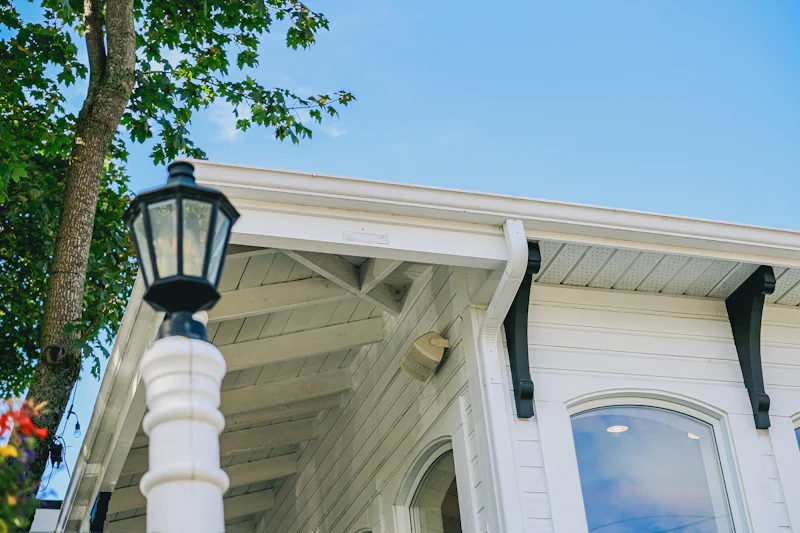 White porch eave with a gutter, downspout and black brackets